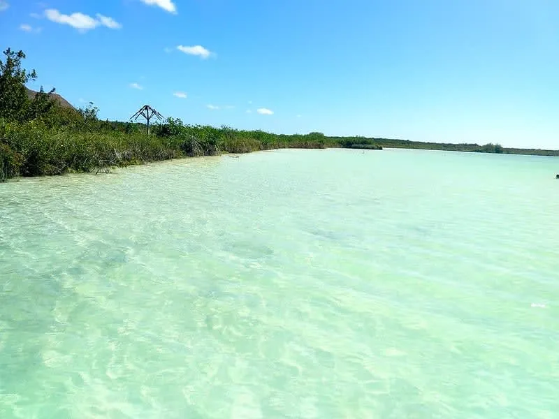 Sunny lagoon shoreline with calm turquoise water and simple wooden shade structures