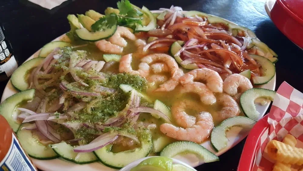 Close view of aguachile with raw shrimp, sliced cucumber, onion, and spicy chile marinade