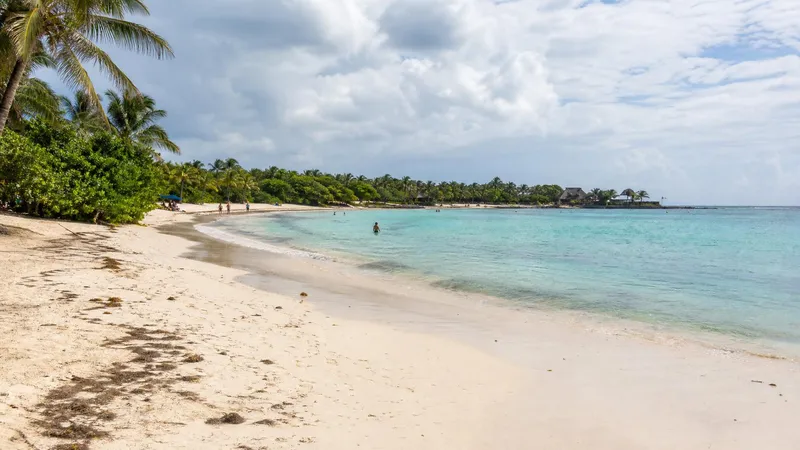 Akumal Bay in July with turquoise water, white sand, palms, and summer Riviera Maya beach weather