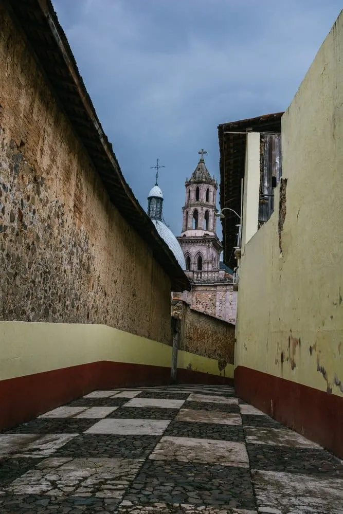 Narrow lane climbing past red-roofed homes in Angangueo