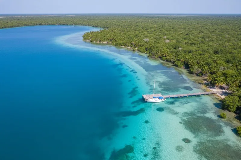 Aerial view of Bacalar Lagoon showing the seven distinct shades of blue and turquoise water created by depth variations and calcium carbonate — the Lagoon of Seven Colors