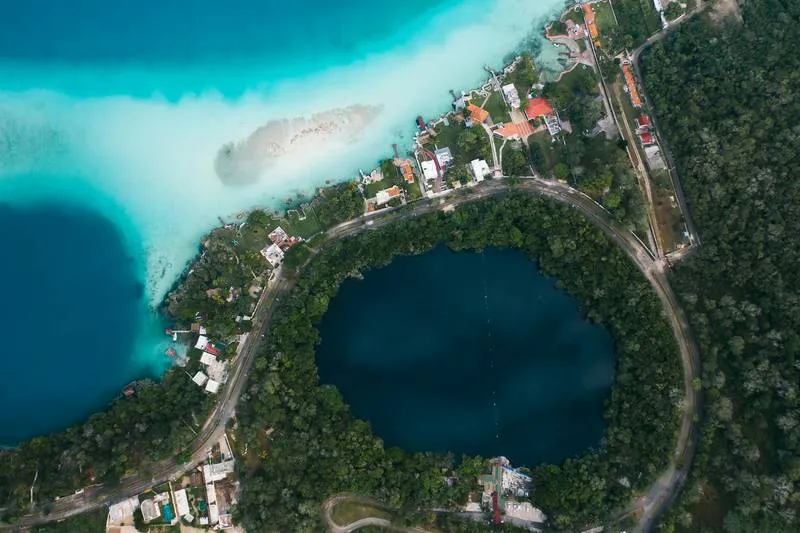 Bacalar Lagoon shimmering in seven distinct shades of blue and green — from pale turquoise near the shore to deep indigo where the freshwater meets the limestone cenote channels