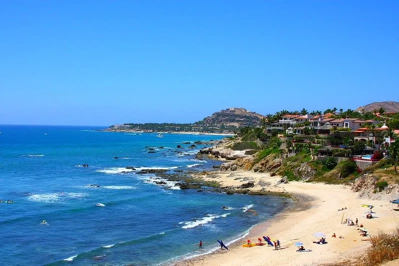 Rocky coastline with hillside houses above a blue beach