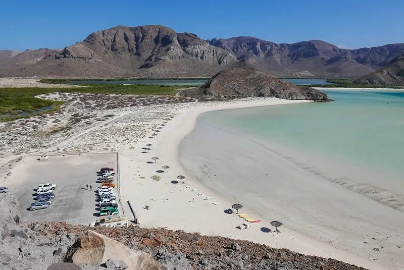 White sandbar curving into shallow turquoise water under a blue sky