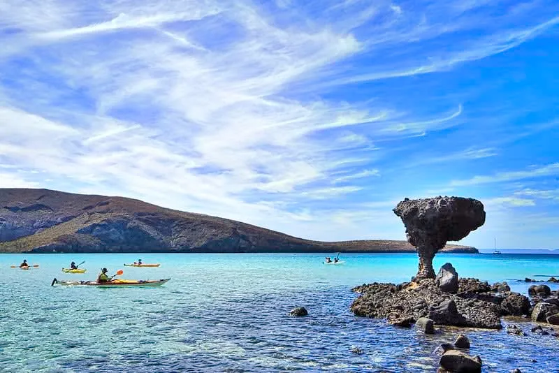 Mushroom-shaped rock beside shallow turquoise water