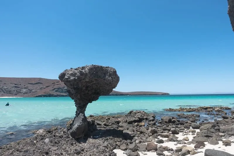 Shallow turquoise bay with white sand and brown hills