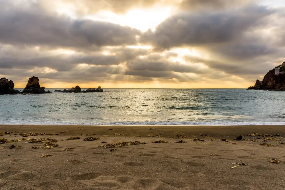 Crescent-shaped Careyes beach with brown sand and calm waves