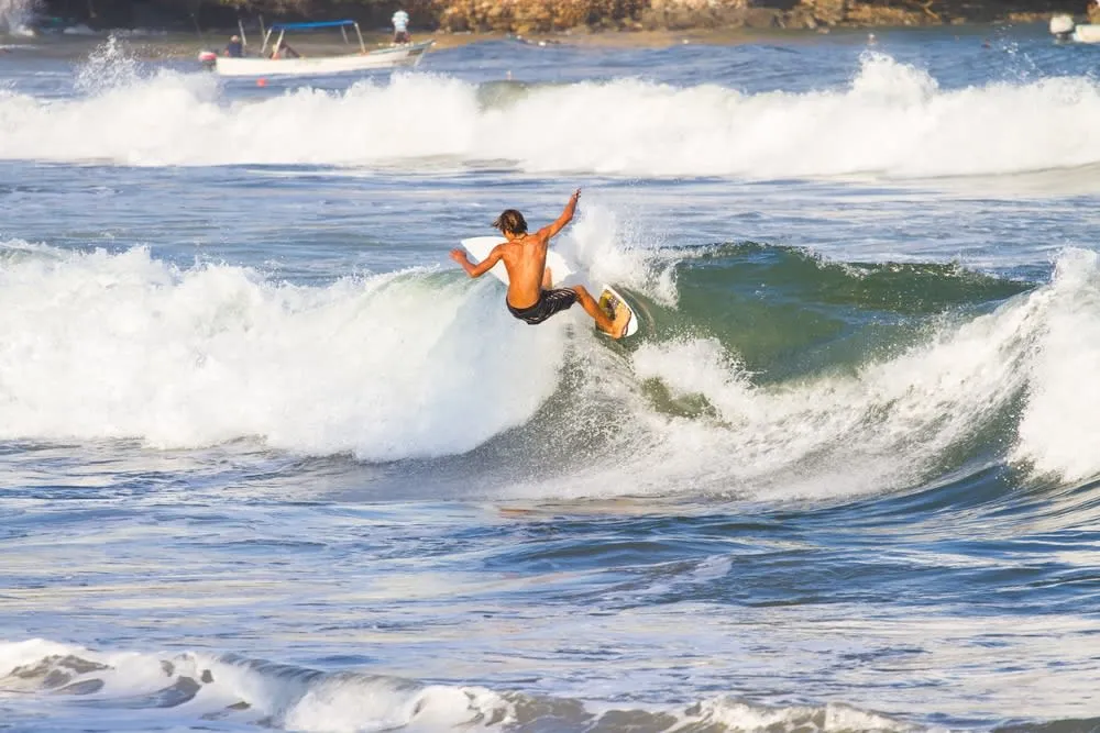 Sayulita beach with surf, umbrellas, and a busy village shoreline