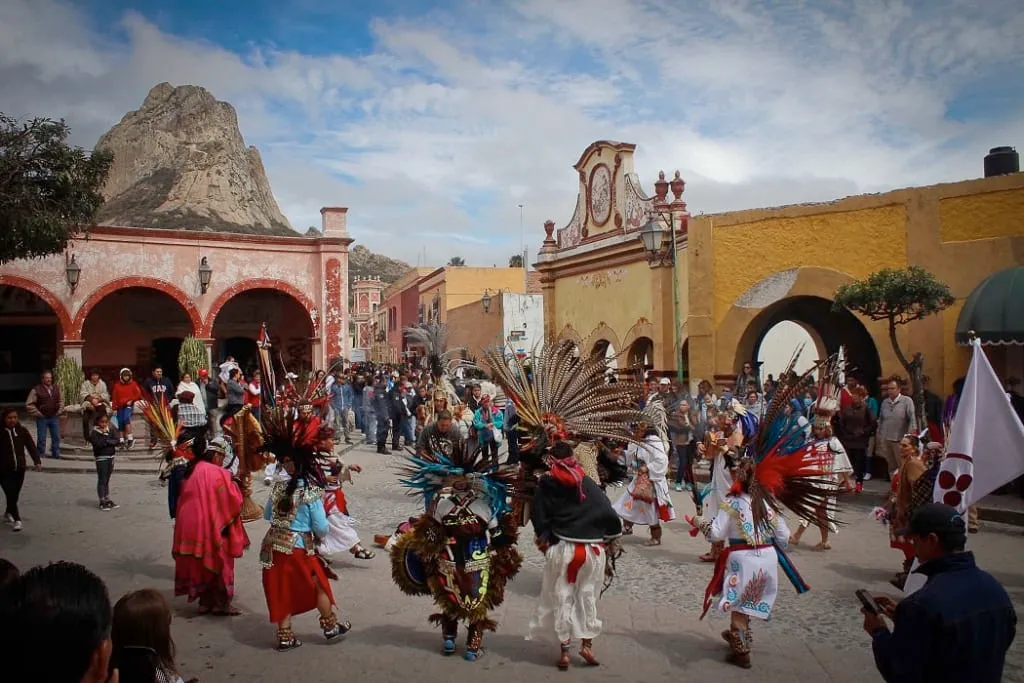 Festival celebration in Bernal, Querétaro with traditional Otomí dress and music near the base of the Peña de Bernal monolith — the town holds cultural festivals throughout the year