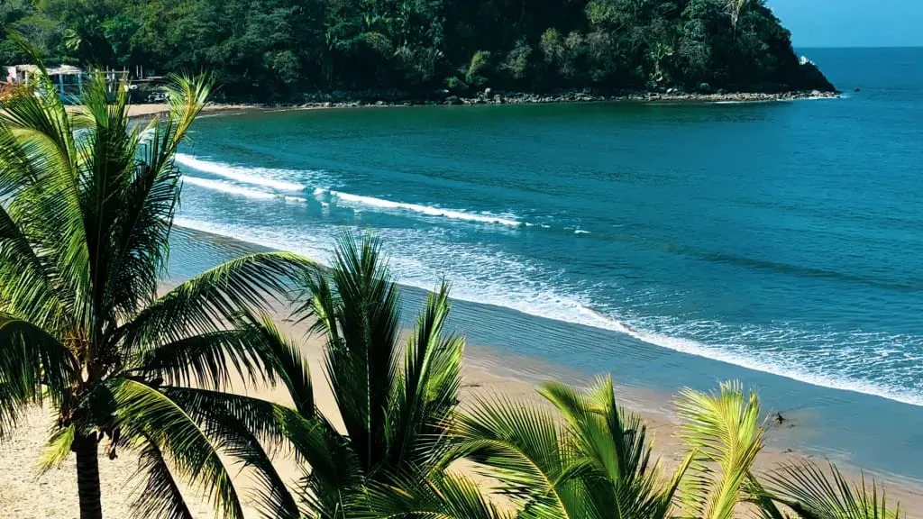 San Blas beach palapas beside dark sand and rolling Pacific surf