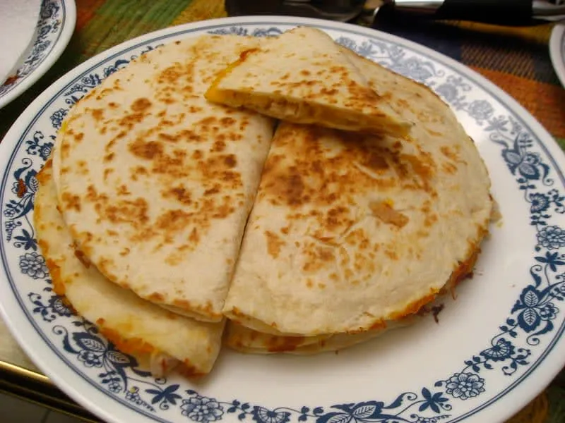 Folded quesadillas served with salsa and fresh garnish