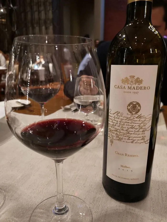 Red wine glass beside Casa Madero bottle