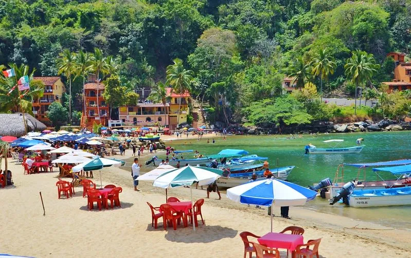 Palapa roofs and panga boats beside the sand at Boca de Tomatlan