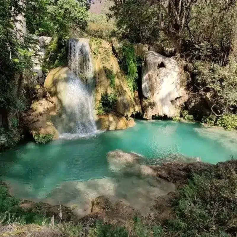 Turquoise waterfall pool surrounded by rocks at Las Granadas, Guerrero