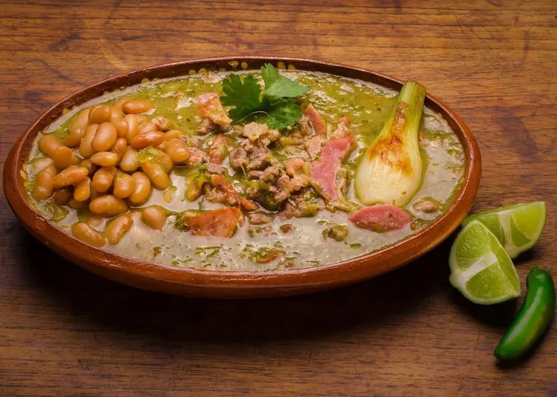 Carne en su jugo — Guadalajara specialty of thin beef strips simmered in their own cooking juices with bacon, tomatillo, jalapeño and white beans, served in a clay bowl
