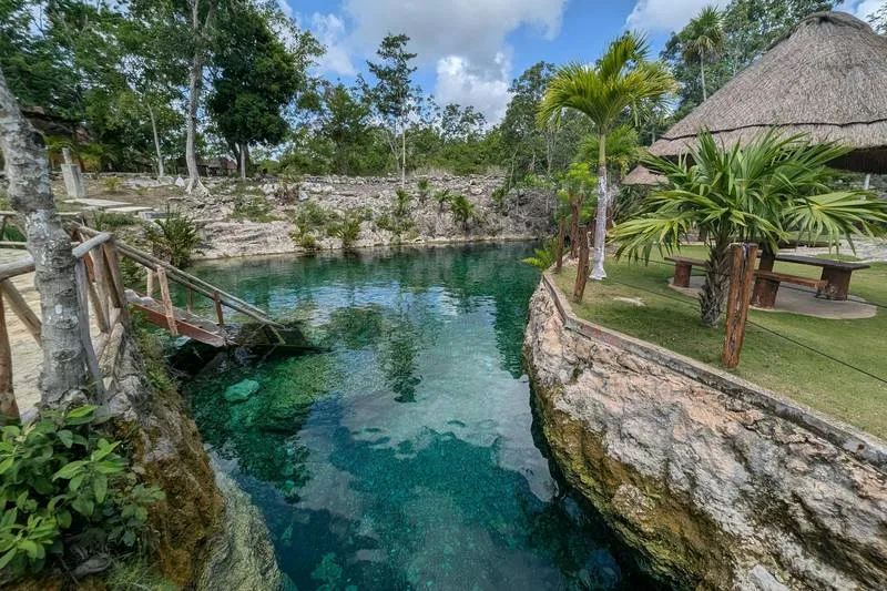 Cenote Ik Kil near Chichen Itza showing the cylindrical limestone opening with hanging vines and clear turquoise water below