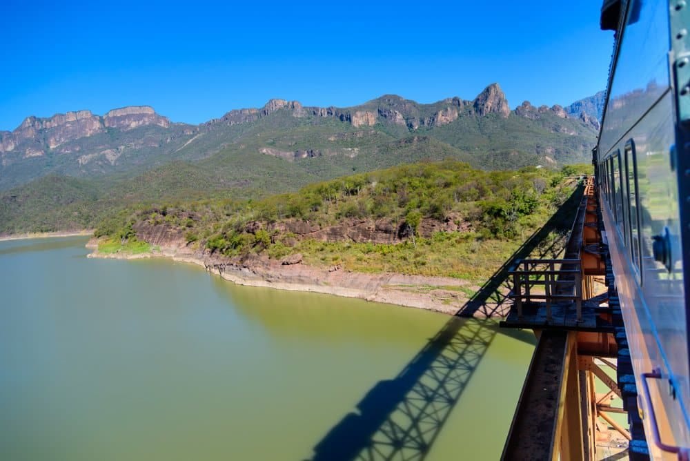 Panoramic view from El Chepe train window of Copper Canyon's dramatic verde-tinted canyon walls