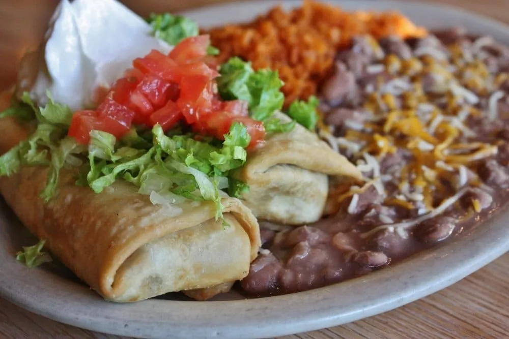 Golden fried chimichanga on a plate with toppings