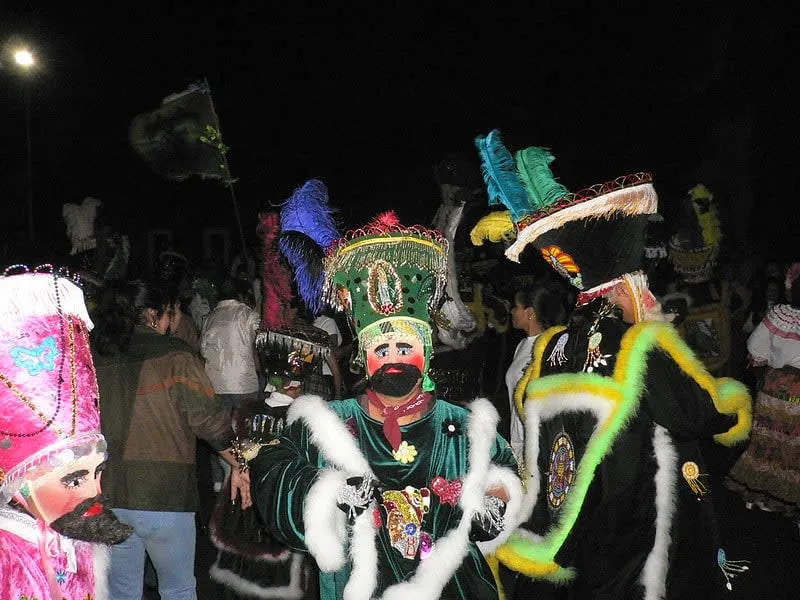 Chinelos dancers in traditional costume — embroidered velvet robes with intricate floral patterns and tall feathered headdresses in Tepoztlán, Morelos