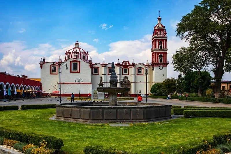 Quiet Cholula street lined with low buildings and sidewalk trees