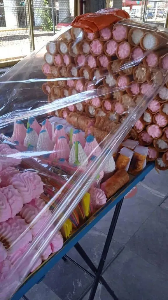 Tall pink and white meringues displayed at a candy stand