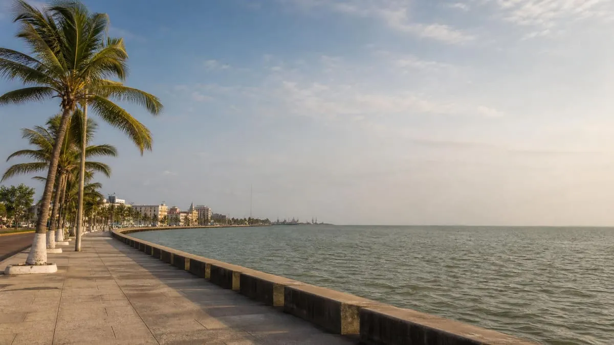 Coatzacoalcos malecon in April with Gulf water, palm trees, warm light, and a humid southern Veracruz sky