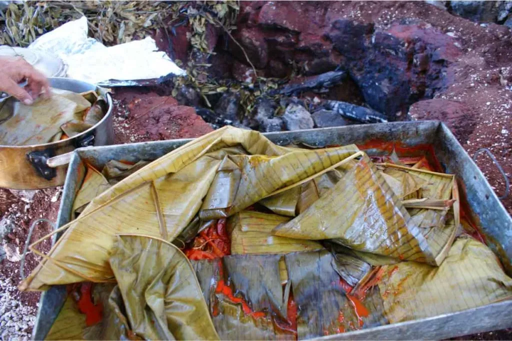 Pork wrapped in banana leaves being prepared for underground pit cooking in Yucatan tradition