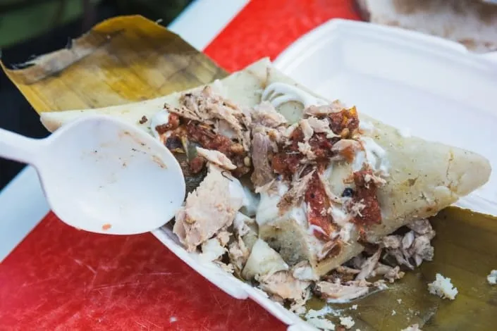 Triangular Michoacan corundas wrapped in green corn leaves on a plate