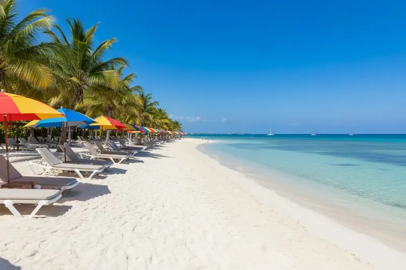 Cozumel west coast beach club with turquoise calm water, beach chairs, and palm trees on a clear sunny day