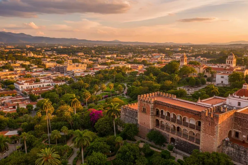 Sunny hillside view over Cuernavaca with garden terraces and red-tiled roofs in dry-season light
