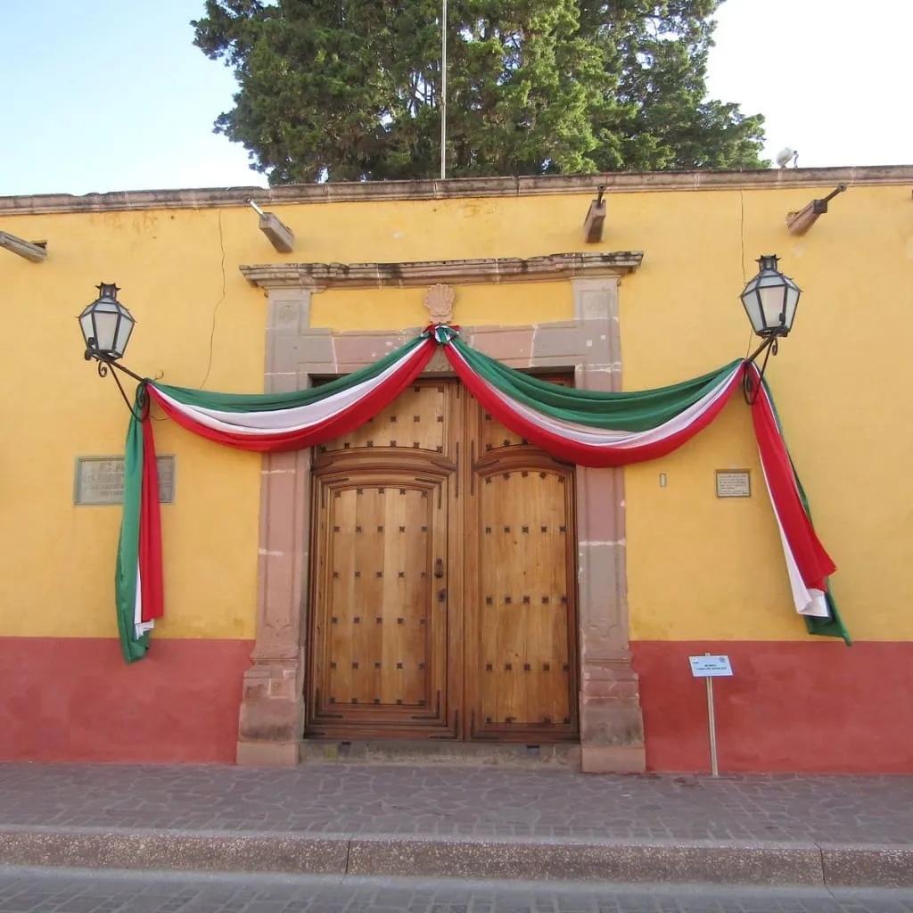 Stone courtyard entrance to Casa Hidalgo Museum with arched doorway and tiled roof