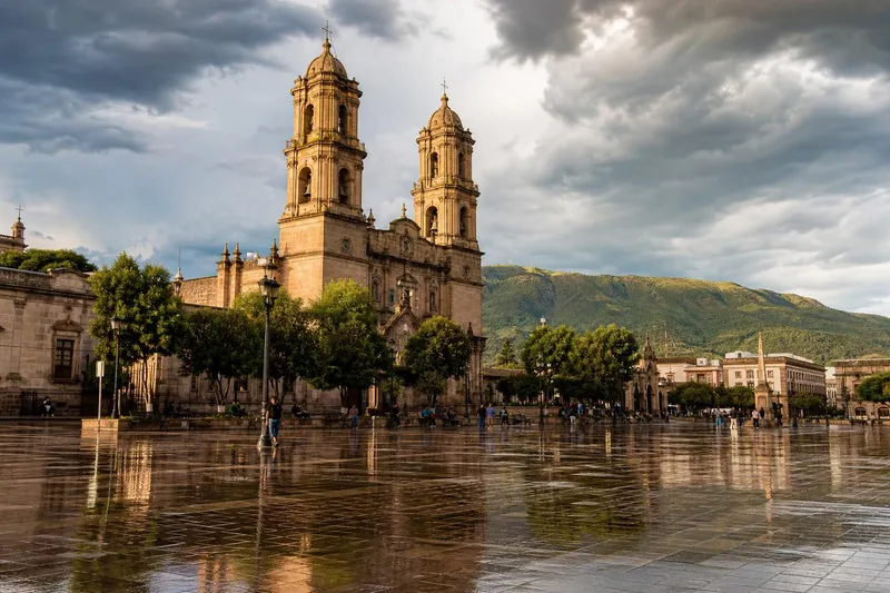 Durango cathedral plaza after August rain with wet stone reflections and storm clouds