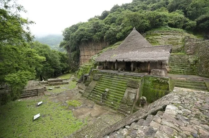 Stone temple entrance carved into a hillside with steps leading up