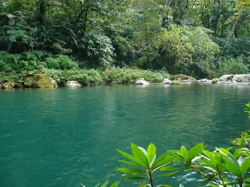 Lake surrounded by green hills under a cloudy sky