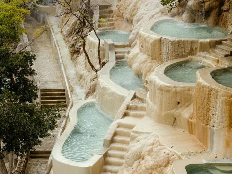 Cascading thermal infinity pools at Grutas de Tolantongo carved into a dramatic canyon wall with turquoise warm water