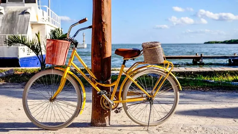 Bike parked on a sandy Holbox Island beach path near the turquoise Caribbean water