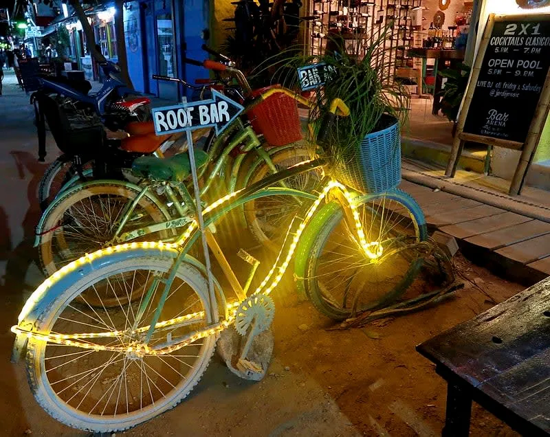Holbox town square at night with restaurant tables, lights, and live music nearby
