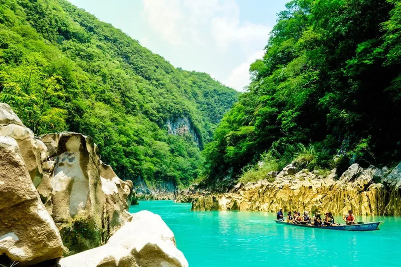 Tall Huasteca waterfall dropping into a clear pool below forested cliffs