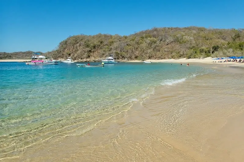 Chachacual Bay in Huatulco National Park with untouched white sand beach and dense tropical forest behind it