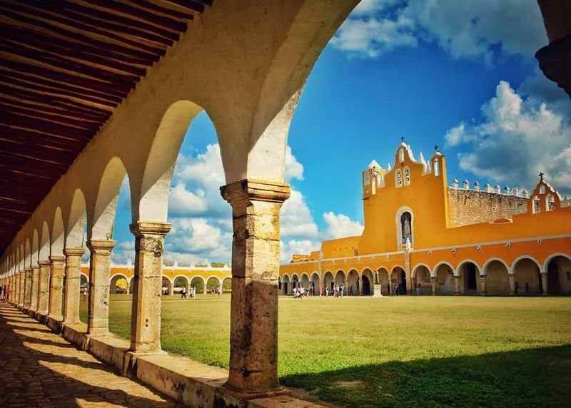 Yellow colonial street in Izamal with bright facades, stone sidewalks, and strong Yucatán sunlight
