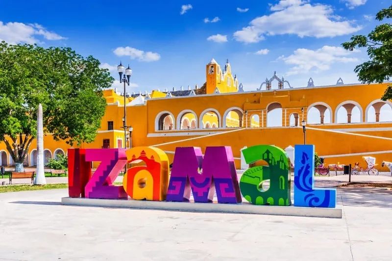 Izamal sign and yellow convent walls under clear March dry-season sky