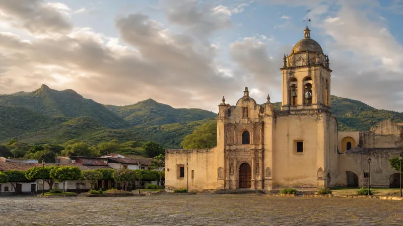 Jalpan de Serra mission in August with green Sierra Gorda hills, morning light, and rainy-season clouds