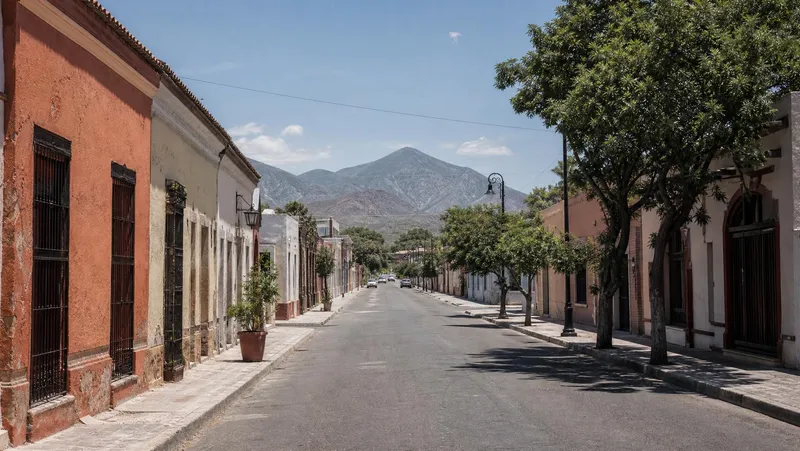 Sunny August street near Linares historic center with Sierra Madre foothills beyond Nuevo Leon rooftops