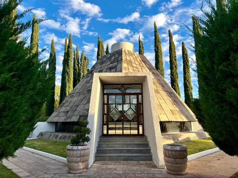 Stone mausoleum beside a paved cemetery walkway and desert plants