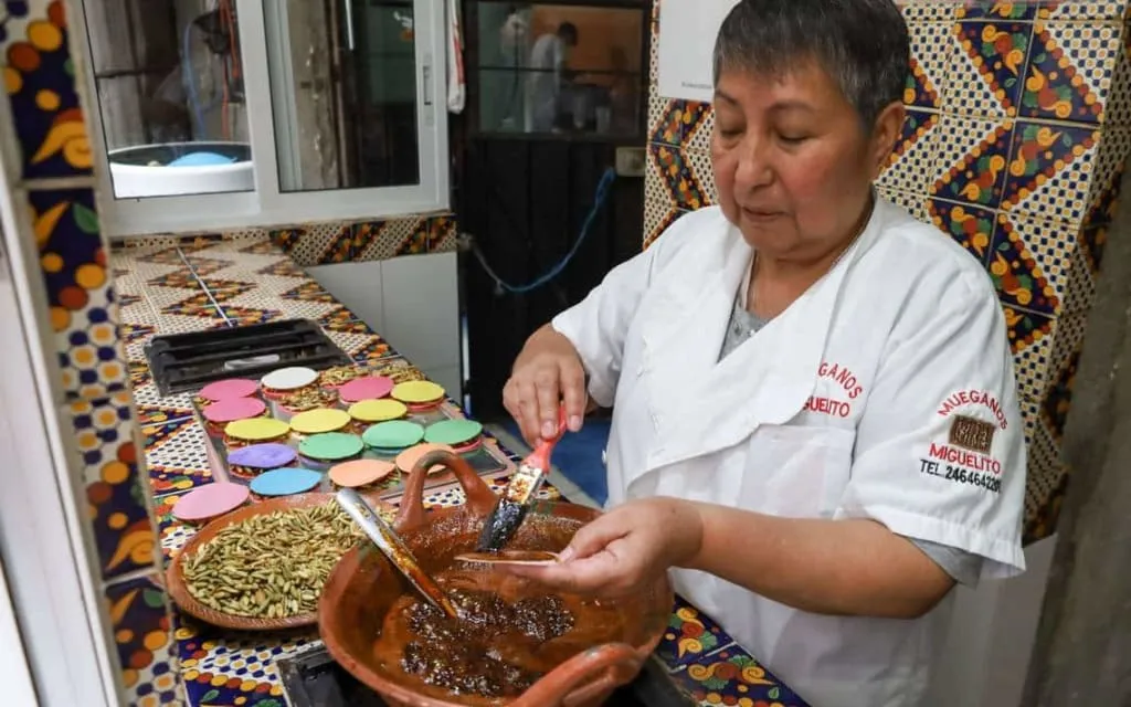 Vendor preparing pepitorias with toasted pumpkin seeds on round wafers