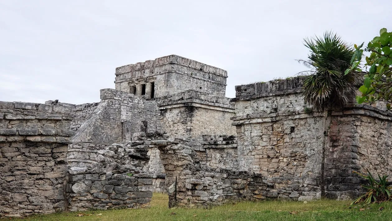 Ancient Maya ruins in the Yucatan jungle — stone temples with carved facades rising above tropical vegetation, similar to structures found throughout Quintana Roo