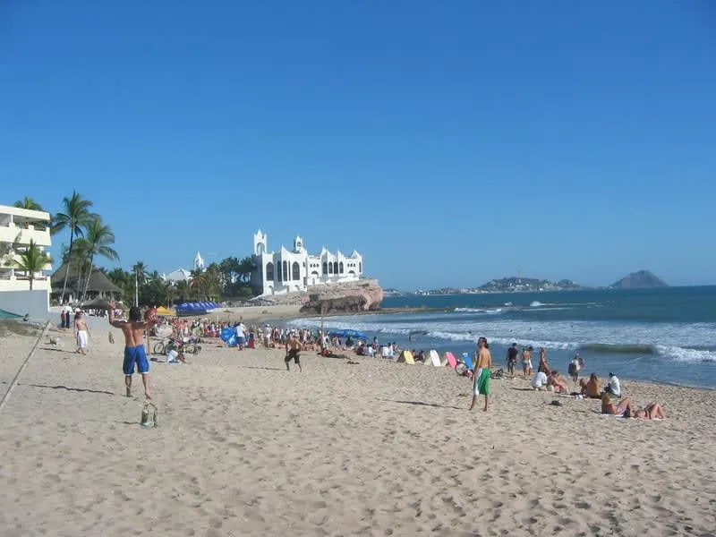 Playa Sabalos in Mazatlan with dark sand and gentle waves north of the Golden Zone