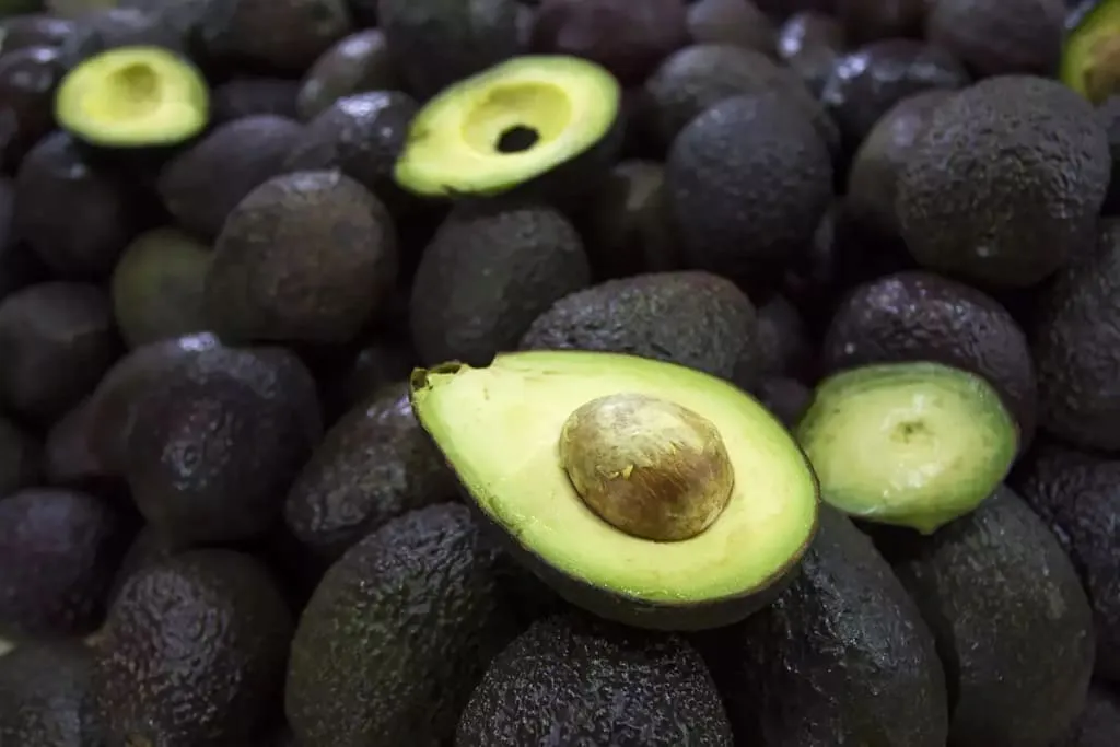 Halved ripe avocado with green flesh and a brown pit