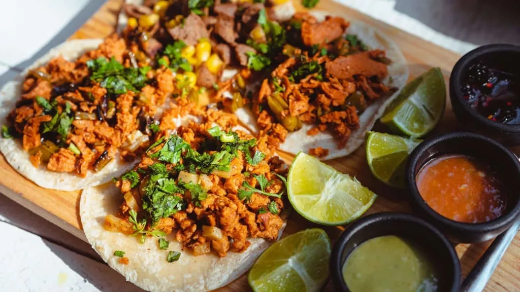 Tacos with salsa, onion, cilantro, and lime on a plate