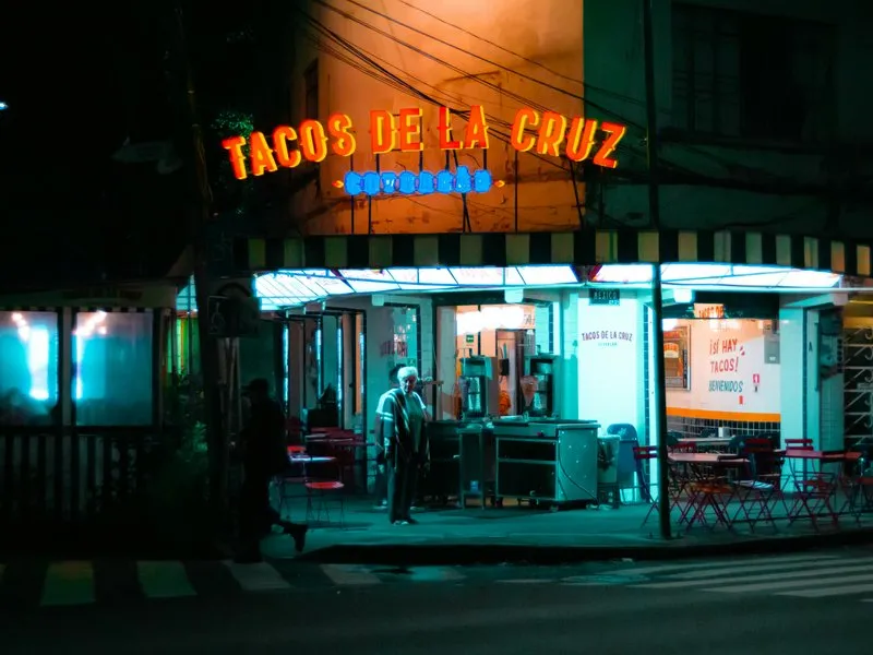 Mexico City taco stand at night with glowing lights and a busy street